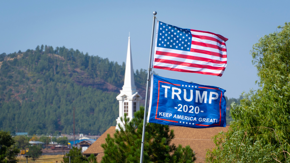 An American Flag and a Trump Flag raised up on a church flagpole in Williams, AZ