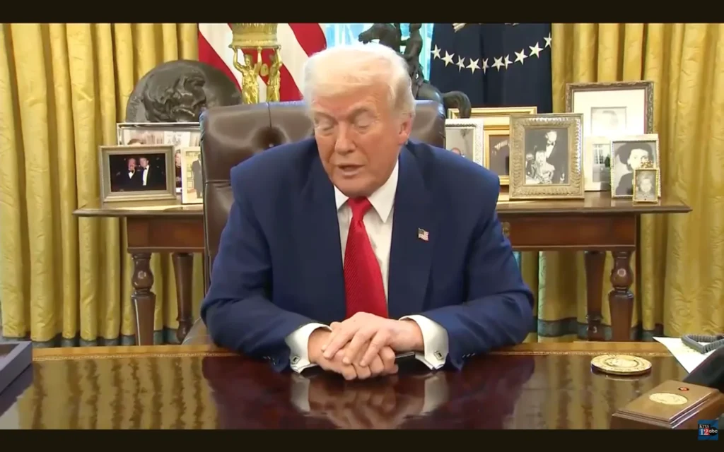Freeze frame of Donald Trump answering questions from the press.