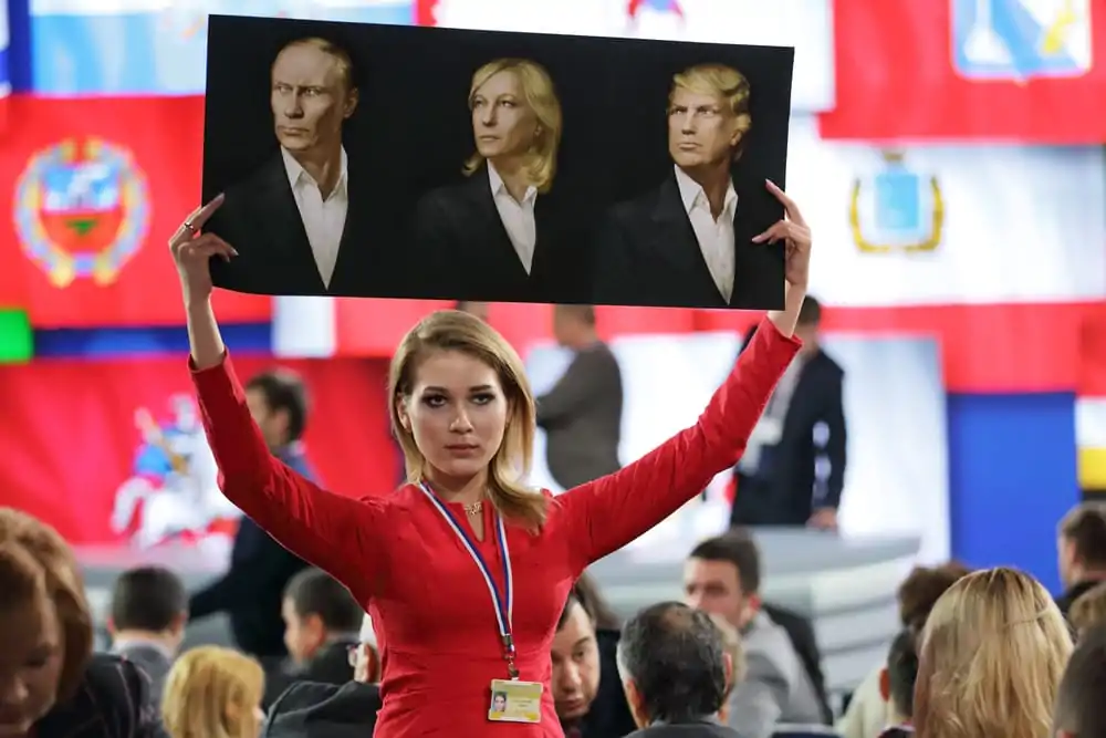 An activist of the NLM Katasonova Maria holds up a poster of Putin, Le Pen and Trump at a Dec. 23, 2016 Putin presser.