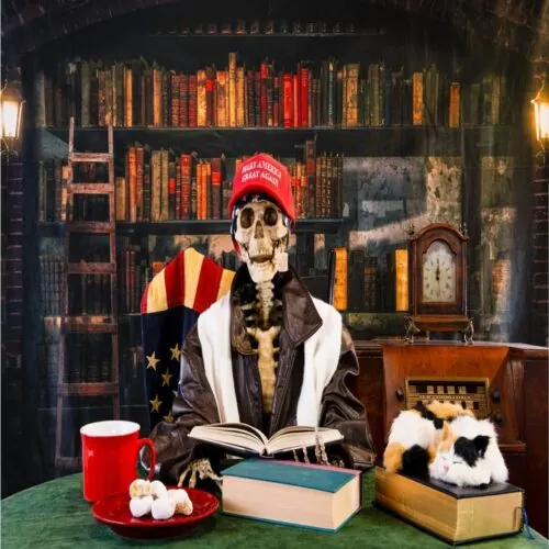 A skeleton with a MAGA hat on, sitting at a desk in a study.